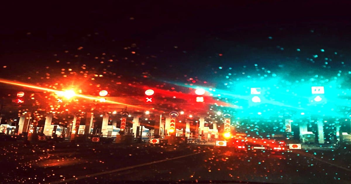 Dynamic routing, c'est quoi ? (contexte agentic AI) - Rain-streaked windshield view of a toll booth at night.