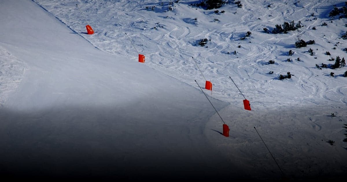 cover article - choisir PSP vs banque e-commerce - Orange markers line a groomed ski slope on a mountain.