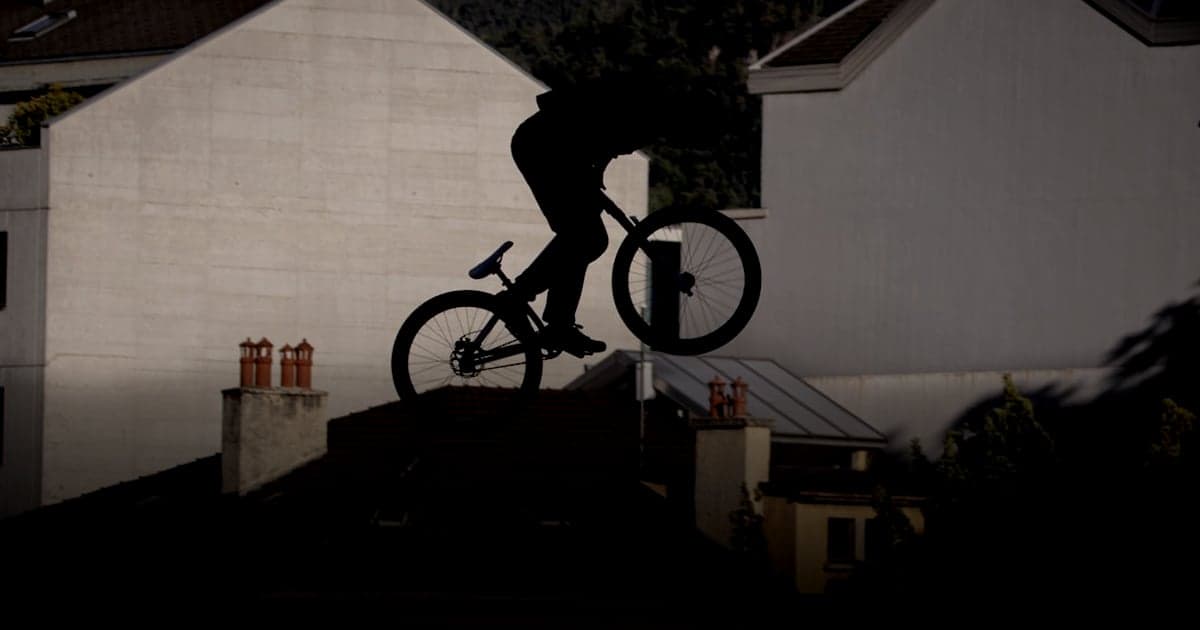 cover article - comparer tops Shopify WooCommerce - Silhouette of a cyclist performing a jump over buildings.